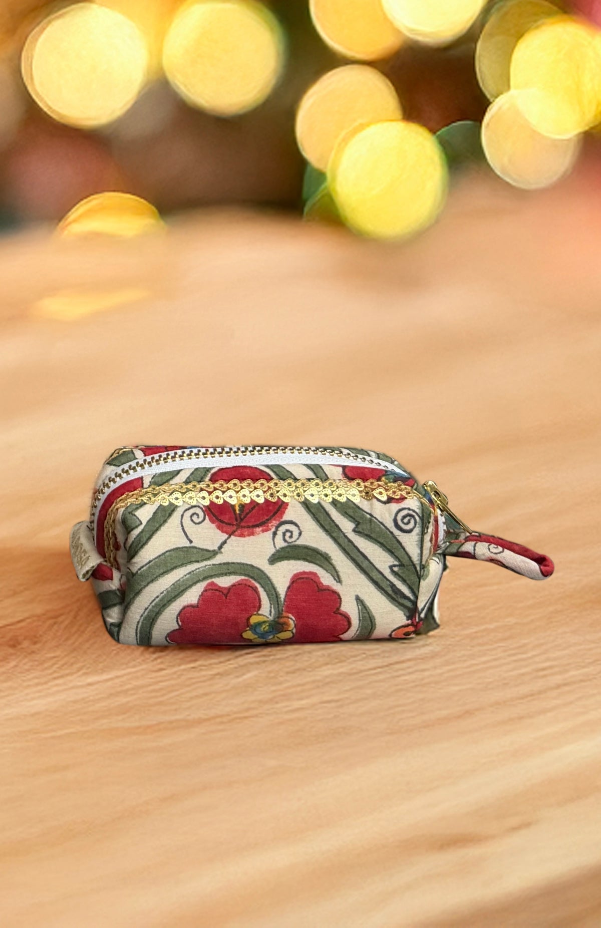 Decorative pouch with floral pattern on a wooden surface with blurred lights in the background